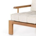 Close-up focusing on tufted seat cushion and one teak leg with metal foot cap