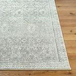 Corner close-up of charcoal rug highlighting fine woven border and low medium pile on natural wood floor