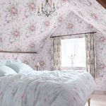 wallpaper applied on angled walls and ceiling in a bright rustic bedroom with floral curtains and bedding