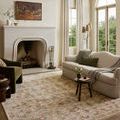 Clarisse rug styled in living room with sofa, armchair, and fireplace showing full rug in room context
