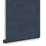 Close-up of navy blue Haptic wallpaper roll hanging vertically with visible bottom edge curl