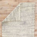 Almand rug partially flipped over revealing consistent pattern on back side on wooden floor