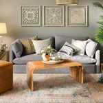 Cascade Coffee Table styled in a living room with gray sofa, decorative pillows, wall art, and a patterned rug