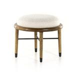 Angled view illustrating ottoman with four tapered oak legs and rounded cushion