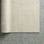 Corner of cream and gray rug layered over blue patterned rug showing contrast in textures