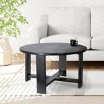 Black coffee table styled in bright room with light gray sofa, plant, and striped rug