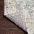 Corner of Rosette Denim Fog rug flipped to reveal sturdy gray woven backing and finished edge