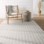 Rug angled in room context showing striped pattern beneath styled wood chair and vase