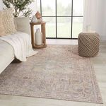 Rug displayed in living room setting with pouf, side table, and sofa partially visible