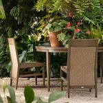 Two Savannah arm chairs with round outdoor table in garden setting with lush greenery