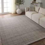 Club rug laid out in bright living room with beige sectional and wood floor