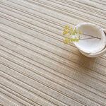 Close view of textured weave with a white bowl and small yellow flowers on rug