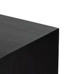Close-up showing round iron knob on upper drawer against black wood