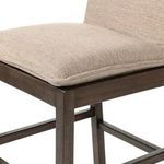Three-quarter side view of stool showing profile of cushioned seat and almond wood frame supports