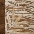 Partial top view of rug corner displaying beige, brown, and green leaf pattern on wood floor