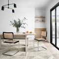 angled view of rug under dining table with two modern chairs and large window