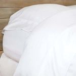 Close detail of bamboo sheet edging and pillowcase seam on a wooden surface