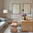 Two identical framed paintings hung side by side on a beige wall in a modern living room with wooden furniture and soft li...
