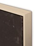 Close-up of light wood frame corner showing texture and subtle paint details on darker canvas edge.