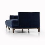 Close-up on navy velvet seat corner tufted with visible stitching and wooden leg