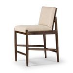 Side angle view showcasing stool’s woven rattan panel and natural linen cushion