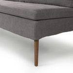 Close-up view of amber oak tapered leg with fabric upholstery wrapping above it
