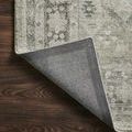 Corner of the rug flipped to reveal a dark gray non-slip backing with a herringbone pattern