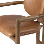 Close-up of right armrest corner with smooth tubular oak wood and caramel leather seat cushion