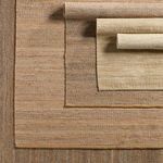 Multiple modern rugs stacked with Rosier rug at the bottom displaying beige and ivory blend