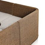 Detailed view of banquette seats with tufting on fabric cushions over woven rattan frame