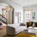 Marcelo chandelier hanging above a living space with a grey curved sofa and colorful abstract rug