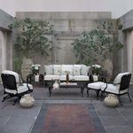 Provance Coffee Table styled in outdoor patio setting with white cushioned armchairs and large stone planters