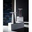Figuration Side Tables styled in modern room setting on white platforms with dark blue accent wall