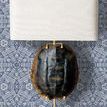 Close-up view of wallpaper behind a decorative gold and black turtle shell lamp with white rectangular shade