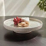 Styled serving stand on dark table with cheese, crackers, and red grapes