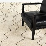Partial view of black leather chair on top of plush Moroccan rug with zigzag design