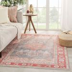 Styled room setting with rug beneath table, sofa, and pouf near bright window