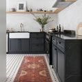 Narrow Loren rug runner placed in black and white tiled kitchen with dark cabinetry and farmhouse sink