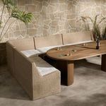 L-shaped banquette styled with wooden dining table in a stone-walled room