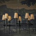 Blackthorn Chandelier shown with tan fabric lamp shades in a dark room setting
