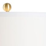 Close-up of brass finial on top of white lamp shade