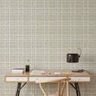 Wallpaper installed on wall behind wooden desk and chair, showing scale and room context of the beige plaid pattern