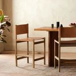 Side view of stool in an interior space next to a wood dining table with candles on top