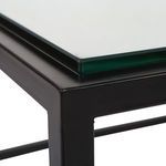 Close-up of coffee table corner showing thickness of tempered glass and matte black frame finish