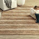 Barcelona rug styled in living room setting with neutral sofa, pouf, and hardwood floor