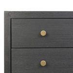 Close-up detail of two brass-finished circular drawer pulls against the black wood veneer