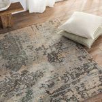 Top-down corner view of the rug with pillows stacked nearby on wood flooring