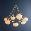 Full chandelier suspended showing six seeded glass shades and curved gold metal bands against dark wall