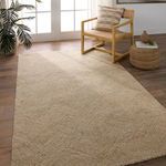 Rug displayed in a bright room setting under chair and woven ottoman on hardwood floor