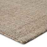 Close-up corner view highlighting edge binding and texture of Sutton natural solid rug